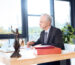 thoughtful mature lawyer sitting at modern office with papers and laptop